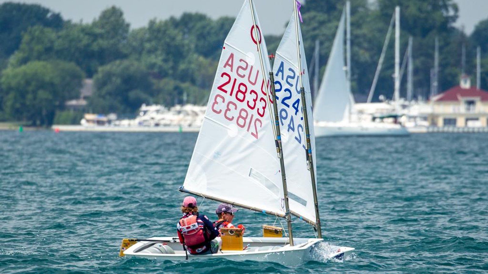 Two young sailors racing an Optimist without a coach nearby