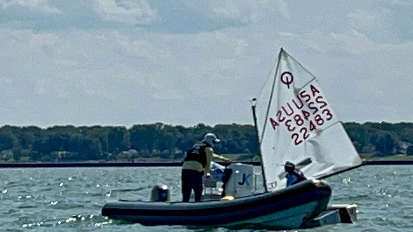 JK Sailing coach boat alongside a young sailor