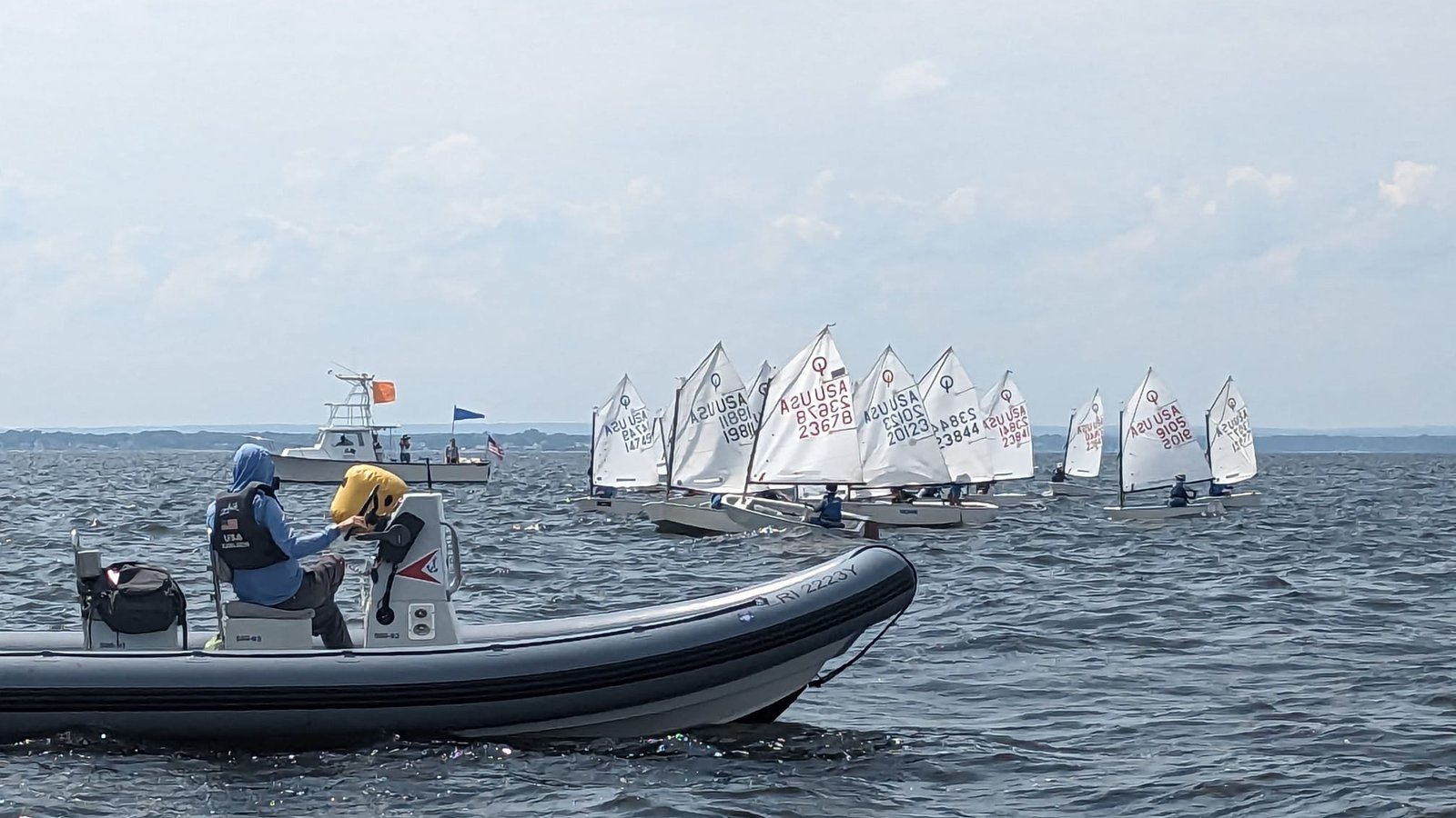 Coach in a RIB watching a fleet of Optimists