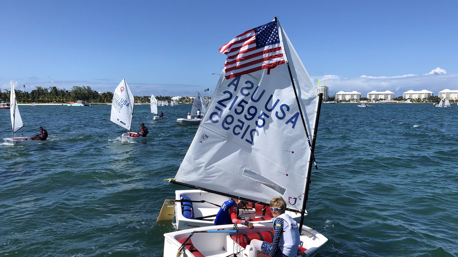 Young Optimist sailor smiling under an American flag